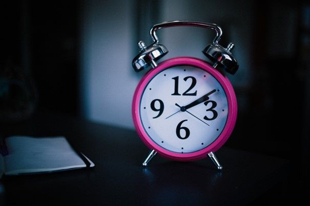 Primer plano de un reloj despertador rosa.
