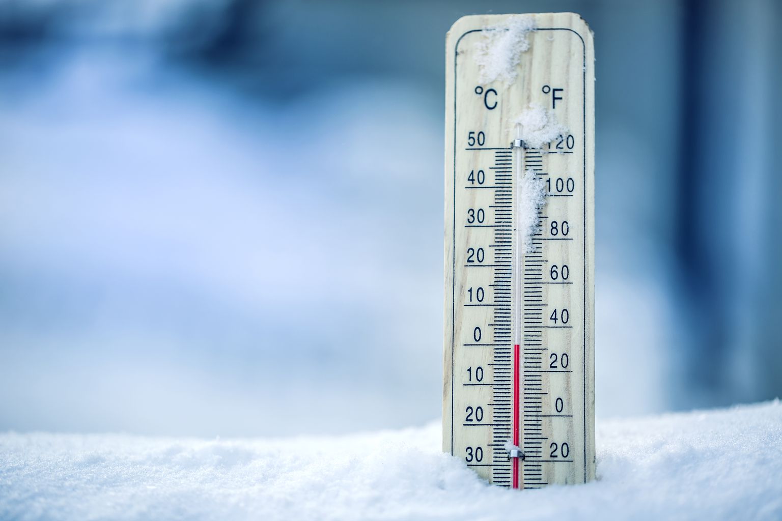 The thermometer on snow shows low temperatures in Celsius or Farenheit.