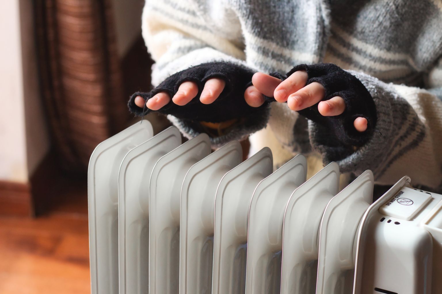 Persona calentándose las manos sobre un radiador