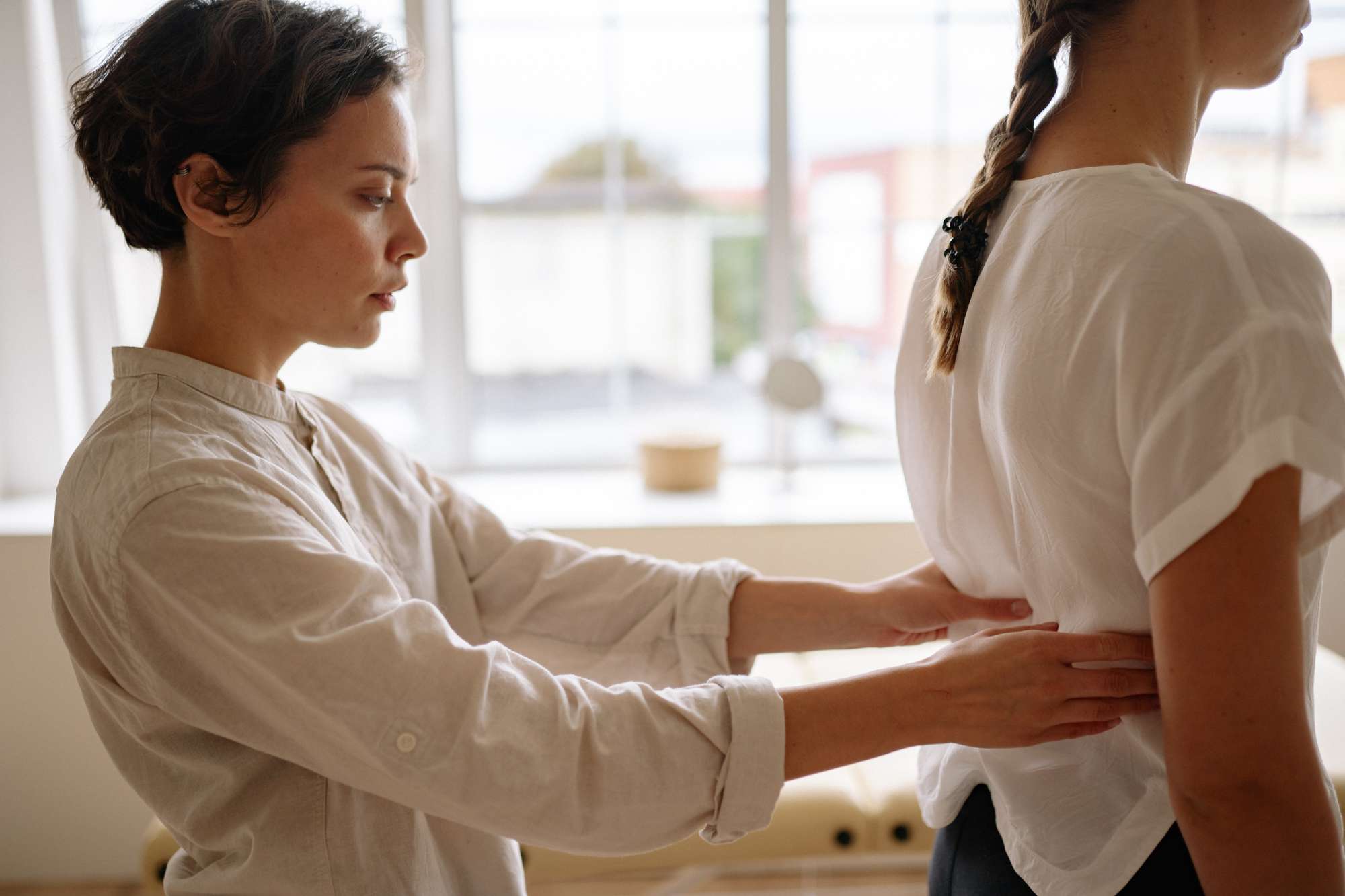 Physiotherapuet berührt Rücken einer Frau