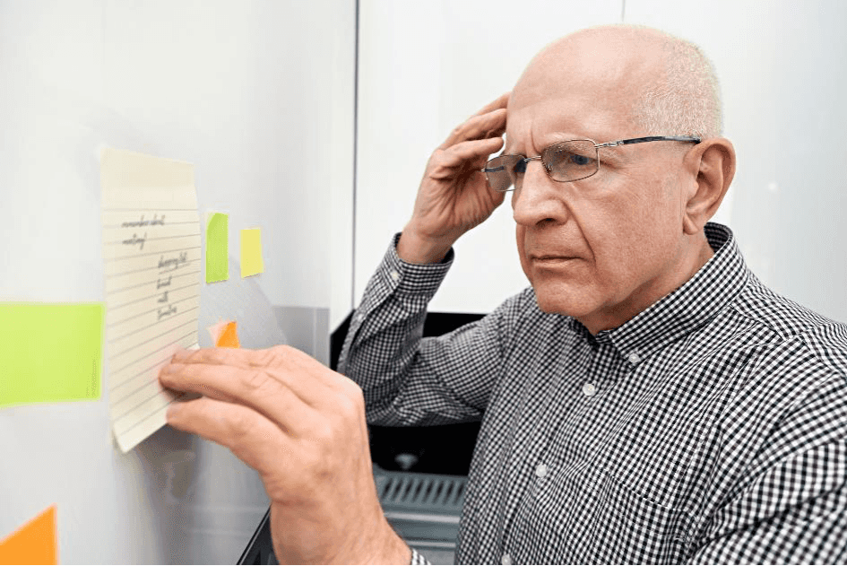 Homem idoso com demência a olhar para notas Homem idoso com demência olha para notas