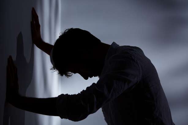 Homem com as mãos encostadas à parede Homem encostado à parede