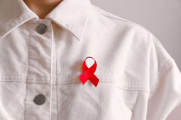 mann-das-bewusstsein-symbol-band-3900469 Uma pessoa com uma camisa branca veste uma fita vermelha, símbolo de solidariedade com pessoas infectadas pelo VIH e doentes com SIDA.