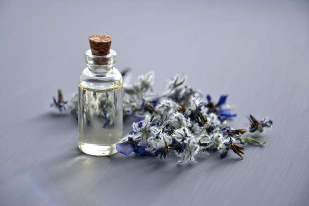 Selektives Fokusfoto Der Flasche Mit Korkdeckel BlĂĽten mit kleiner Glasflasche. Drinnen ist ein aromatisches Ă–l.