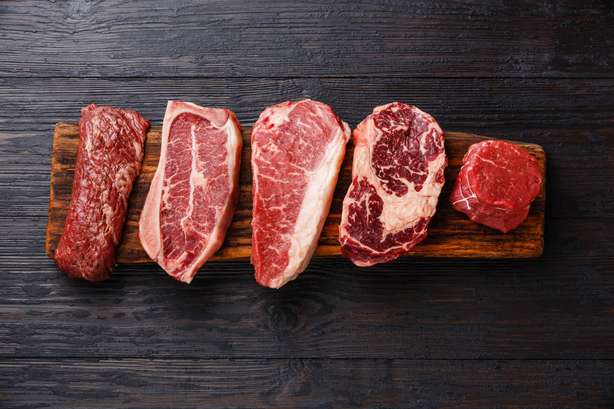 Rotes Fleisch wird auf einem Holzbrett präsentiert Variety of Raw Black Angus Prime Fleisch Steaks Machete, Blade auf Knochen, Striploin, Rib eye, Tenderloin Filet Mignon auf Holzbrett Kopienraum