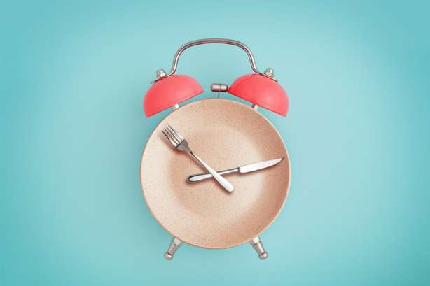 Bord met bestek in de vorm van een wekker. Wekker en bord met bestek. concept van intermittent fasting, lunch, dieet en gewichtsverlies