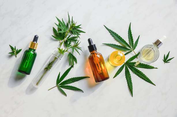 Unterschiedliche Glasflaschen mit CBD-Öl. Verschiedene Glasflaschen mit CBD-Öl, THC-Tinktur und Hanfblätter auf Marmorhintergrund. Flachlage, Minimalismus. Kosmetik CBD Öl.