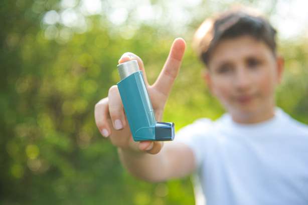Journée mondiale de l'asthme. Un homme a un agent de l'asthme dans ses mains sur les fonds du parc. Le garçon en T-shirt blanc avec un inhalateur pour l'asthme. Un garçon en T-shirt blanc tient un inhalateur pour l'asthme devant la caméra. En arrière-plan, une nature ensoleillée.