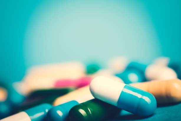 Grüne und gelbe Arzneimittel und Antibiotika auf blauem Hintergrund. Arzneimittel-grüne und gelbe Tabletten oder Kapseln auf blauem Hintergrund mit Kopienraum.Verschreibung von Arzneimitteln zur Behandlung. Arzneimittel zur Heilung in Behältnissen für die Gesundheit. Antibiotika