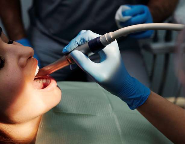 Une personne portant des gants en latex bleu vérifie les dents d'un patient Enregistrement d'un examen dentaire